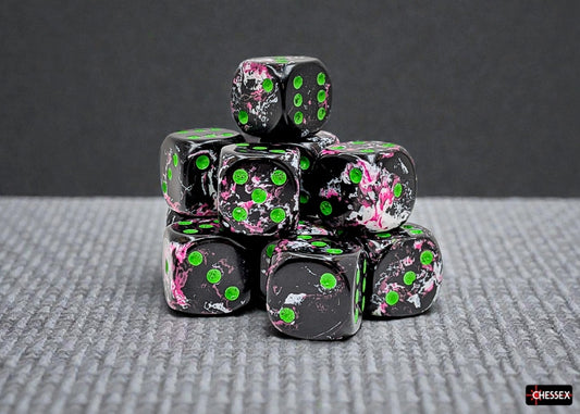 Stack of black dice with white, pink, and green brush patterns and green pips on a gray surface